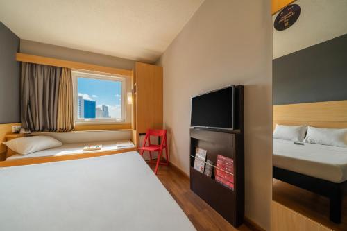 a hotel room with a bed and a tv at ibis Sorocaba in Sorocaba