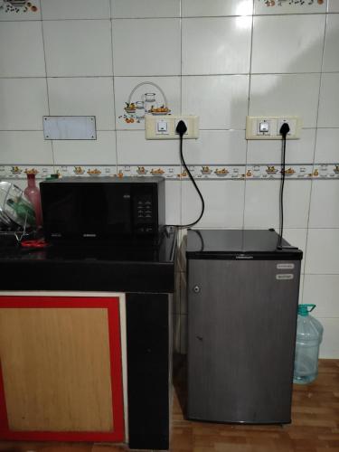 a kitchen with a microwave and a trash can at Gruham Malpe Beach Homestay Udupi in Malpe