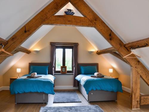 two beds in a attic room with wooden beams at Llaethdy-milkhouse in Talgarth