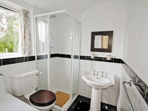 a white bathroom with a toilet and a sink at Swiss Cottage - E5375 in Alrewas