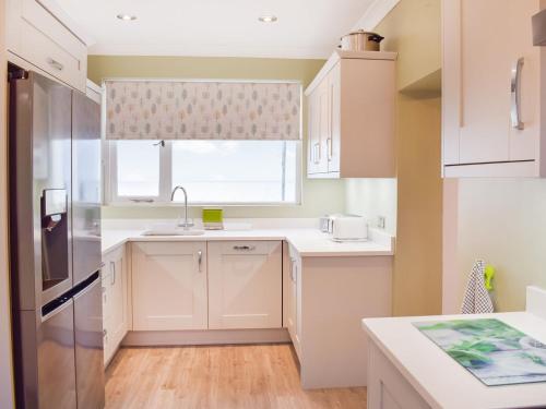a kitchen with white cabinets and a window at Mainslea - Uk36872 in Dunure