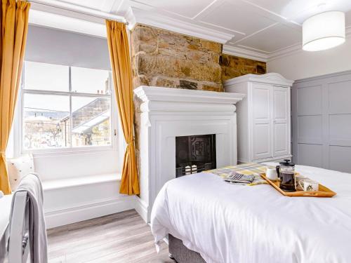 een slaapkamer met een wit bed en een open haard bij Well Strand in Rothbury
