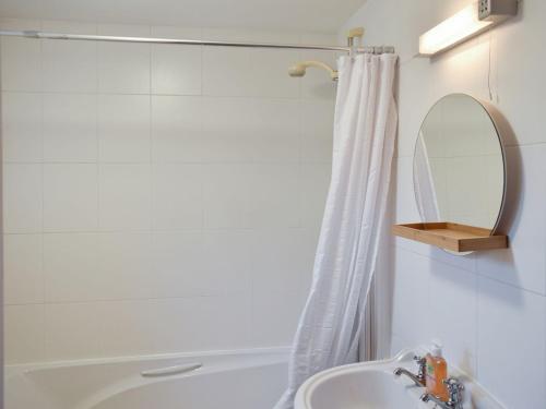 a bathroom with a shower and a sink and a mirror at Quarry Cottage in Penrith