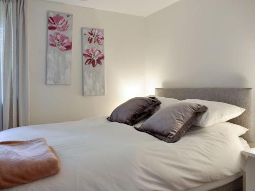 a white bed with three pillows on top of it at Quarry Cottage in Penrith