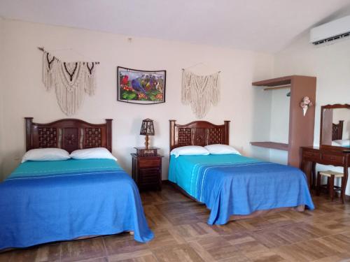 two beds in a room with blue sheets at Villas victoria mirador in Zihuatanejo