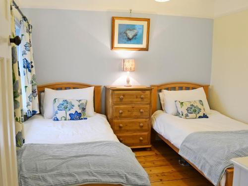 two twin beds in a room with a dresser at Penhill Farm Cottage in Fremington