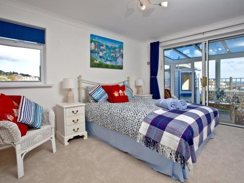a bedroom with a bed and a chair and windows at Sea Salt Lodge in Torquay