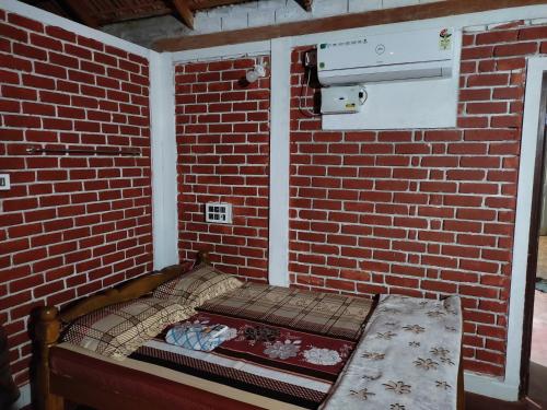 a small brick wall with a bed in a room at Gruham Malpe Homestay Udupi in Malpe