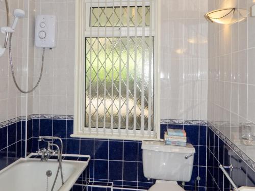 a bathroom with a tub and a toilet and a window at The Garden Flat in Torquay