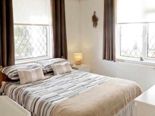 a bed in a bedroom with two windows at The Garden Flat in Torquay