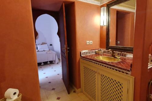 baño con lavabo, espejo y cama en Riad Le Manzil Beldi en Marrakech