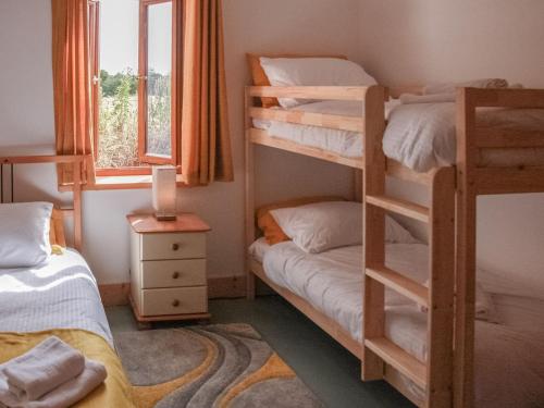 Long Stratton的住宿－Haycart Barn，一间卧室设有两张双层床和一扇窗户。