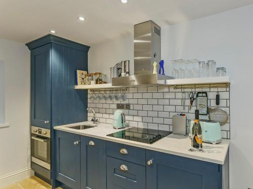 a kitchen with blue cabinets and a sink at Healey Cottage in Kirkburton