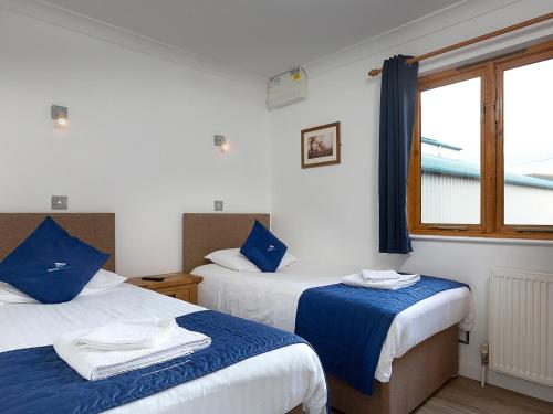 a bedroom with two beds with blue and white sheets at Mallard in Wroxham