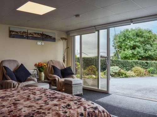 a bedroom with a bed and chairs and a sliding glass door at Lynch Annexe in Appledore