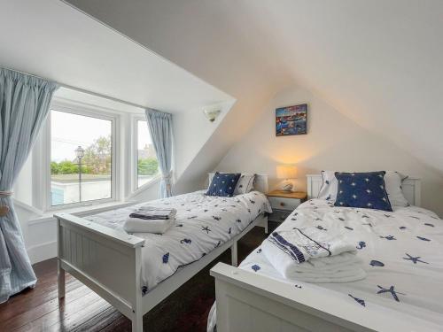 two beds in a room with a window at Pink Cottage in Nairn