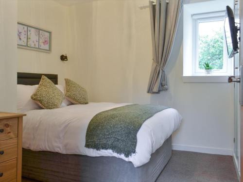 a bedroom with a large bed with a window at Blackmill Cottages No 2 in Taynuilt