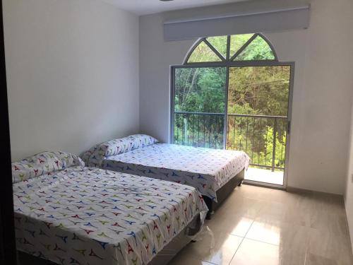 two beds in a room with a window at Casa Flandes Tolima in Flandes