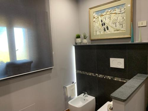 een badkamer met een toilet en een foto aan de muur bij Casa Gino Petrulli Etna, villa con piscina in Zafferana Etnea