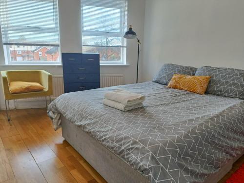 ロンドンにある2 Bed Functional House Close to Manor Park Train Stationのベッドルーム1室(ベッド1台、ドレッサー、窓2つ付)