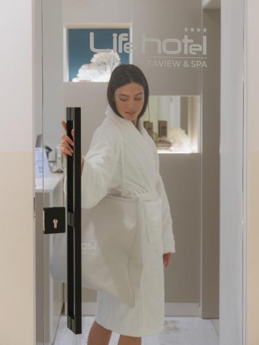 a woman in a white robe standing in a store at Life Hotel Seaview & Spa in Porto Recanati