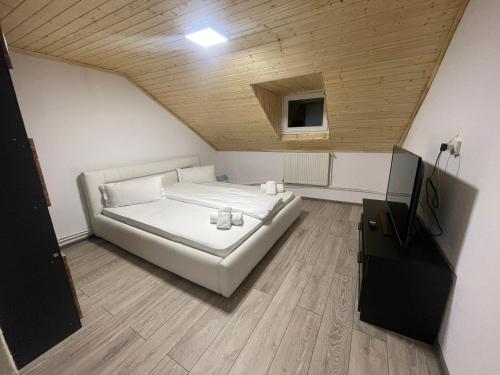 ein weißes Bett in einem Zimmer mit Holzdecke in der Unterkunft Vila Rustik Straja in Lupeni