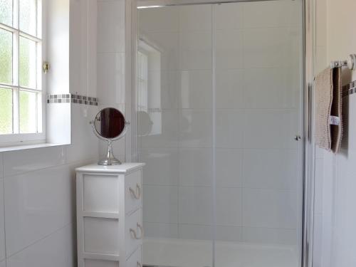 a white bathroom with a shower with a mirror at Repton Cottage - 25348 in Findern