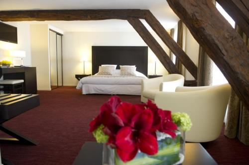 a hotel room with a bed and a vase of flowers at Hôtel Burgevin in Sully-sur-Loire