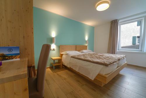 ein Schlafzimmer mit einem großen Bett und einem Fenster in der Unterkunft GH Hotel Monzoni in Pozza di Fassa