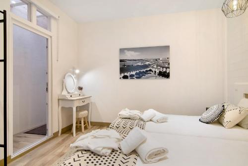 a white bedroom with a bed and a mirror at Casa na Travessa in Faro