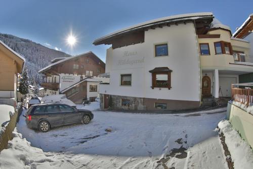 een auto geparkeerd voor een gebouw in de sneeuw bij Haus Hildegard in Gerlos