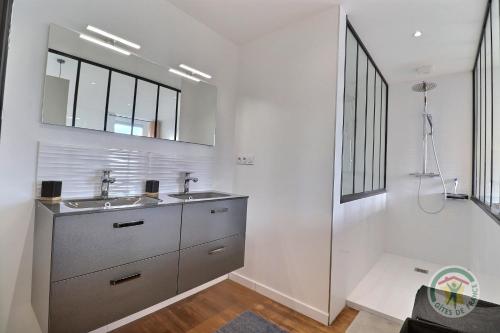 a bathroom with two sinks and a mirror at Chambre à la ferme TORCE in Torcé