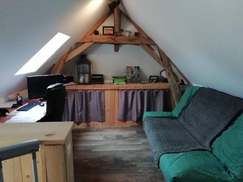 una sala de estar con un sofá verde en un ático en Charmante maison de village en Val de Loire, en Rivarennes