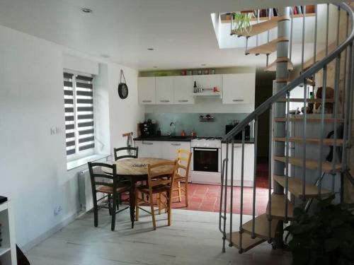 una cocina con mesa y sillas y una escalera en Charmante maison de village en Val de Loire, en Rivarennes