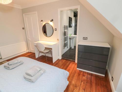 a bedroom with a bed and a desk and a mirror at Glenander in Bamburgh