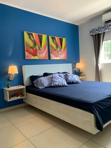 a bedroom with a bed with three pictures on the wall at Lilu Apartments Curaçao in Willemstad