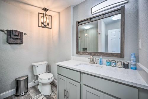 a bathroom with a toilet and a sink with a mirror at Apopka Home with Yard and Grill Near Wekiwa Springs! in Apopka