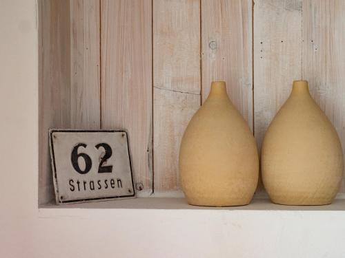 three vases sitting on a shelf next to a clock at Dolomitenloft in Strassen