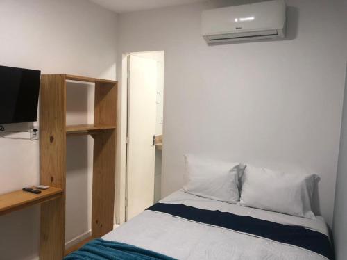 a bedroom with a bed with a shelf and a television at Pousada LuMar Maragogi in Maragogi