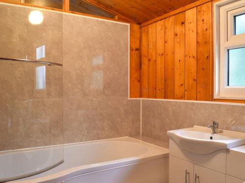 a bathroom with a tub and a sink at Cedar Lodge in Ellington