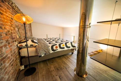 um quarto com uma cama e uma parede de tijolos em L'atelier de Liège: Tranquillité & Effervescence em Liège