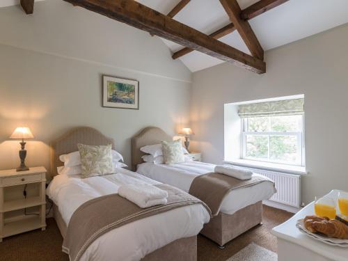 two beds in a room with a window at Helwith Cottage - Ukc3455 in Marrick