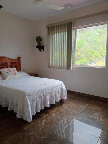a bedroom with a bed and a large window at Villas victoria mirador in Zihuatanejo