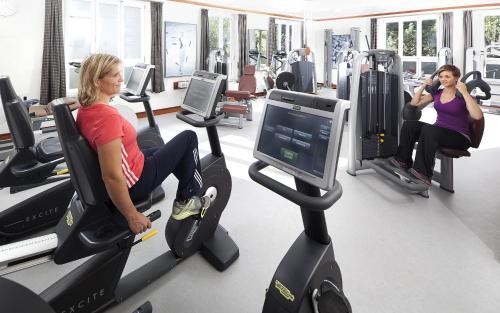 two women riding on exercise bikes in a gym at Kneipp- und Wellvitalhotel Edelweiss in Bad Wörishofen