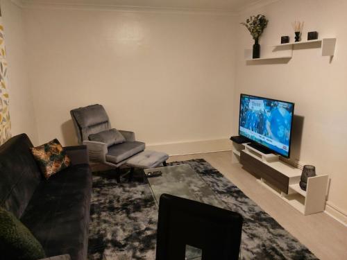 a living room with a couch chair and a television at Heronsgate GH009 in Abbey Wood