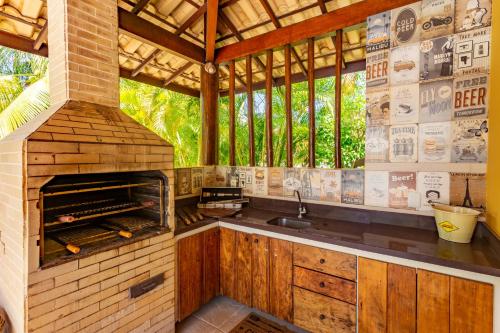 a kitchen with an outdoor kitchen with a brick oven at Reserva Imbassaí - Casa C02 Orquídeas in Imbassai