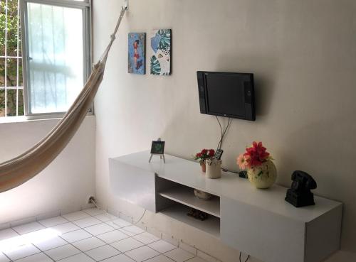 uma sala de estar com televisão numa parede branca em Apt Candeias para 6 pessoas no Recife