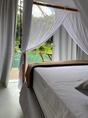 a bedroom with a bed and a large window at Chalés da Floresta in Porto Seguro
