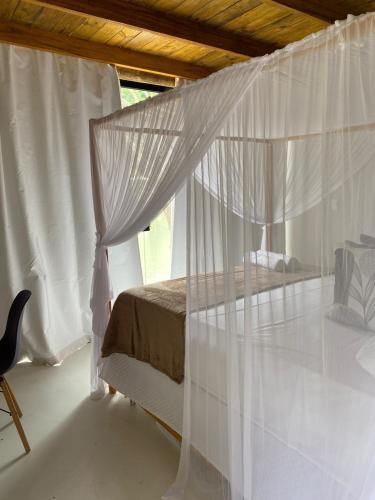 a bedroom with a bed with white mosquito nets at Chalés da Floresta in Porto Seguro