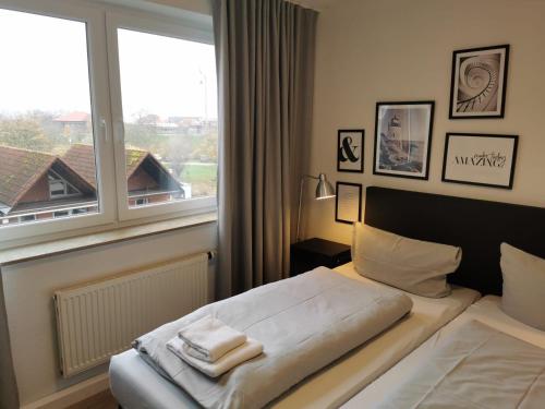 een slaapkamer met een bed en een groot raam bij FeWo Nordsee-Perle Meerblick - Horumersiel in Horumersiel